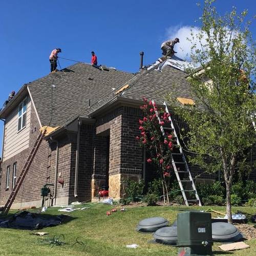 Roofer works on shingle roof.