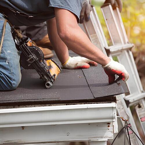worker repairing a shingle roof